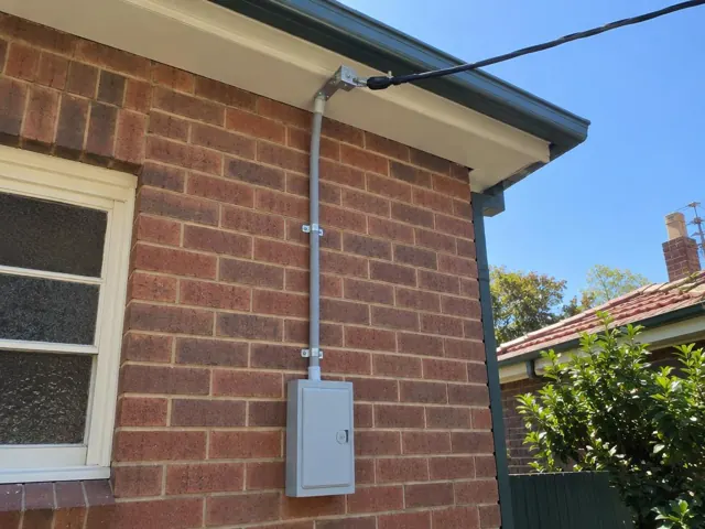 Brick house exterior with new overhead service cable and point-of-attachment bracket near the eaves in Cammeray